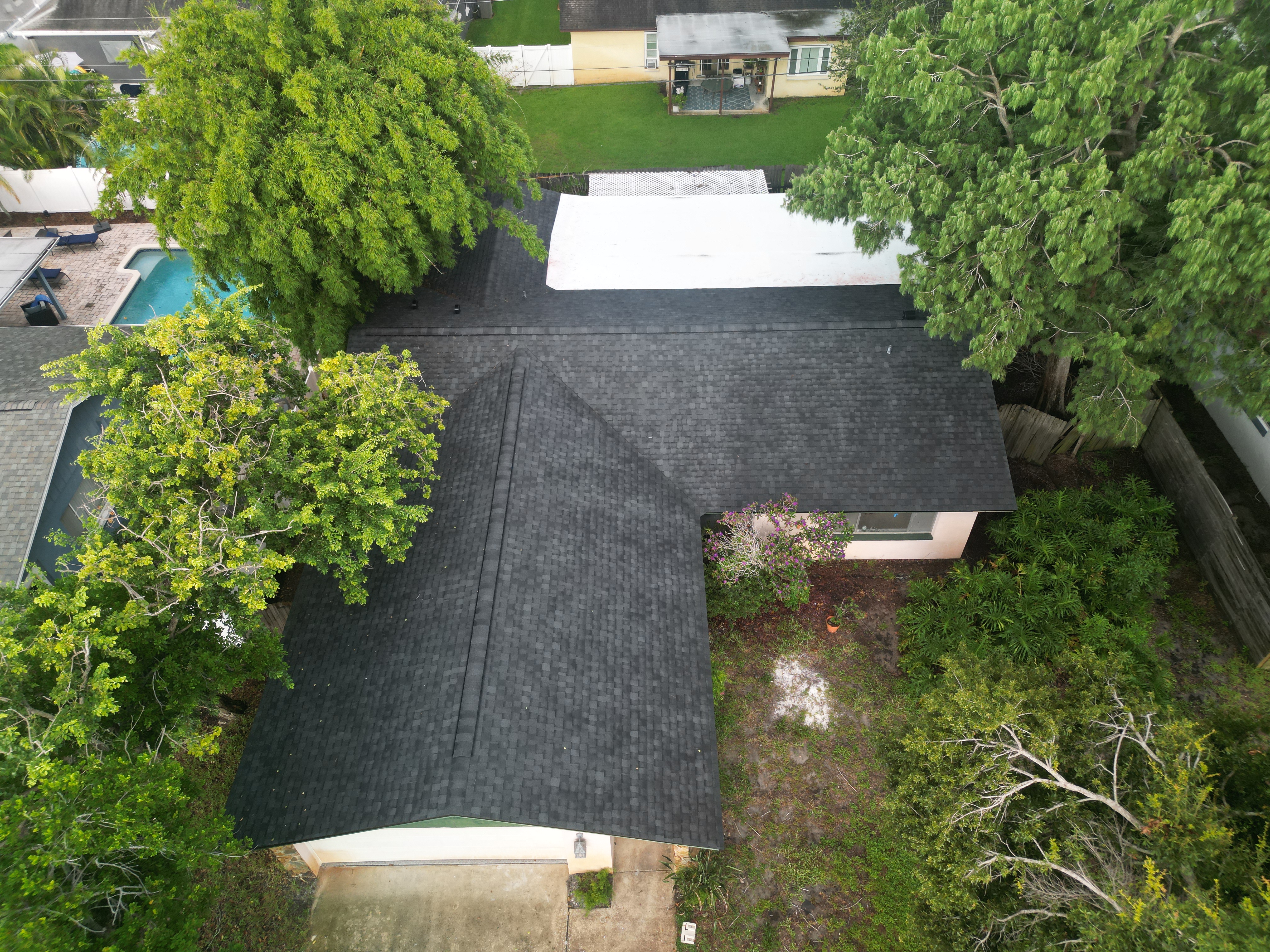 Completed charcoal shingle roof on a home with a pool