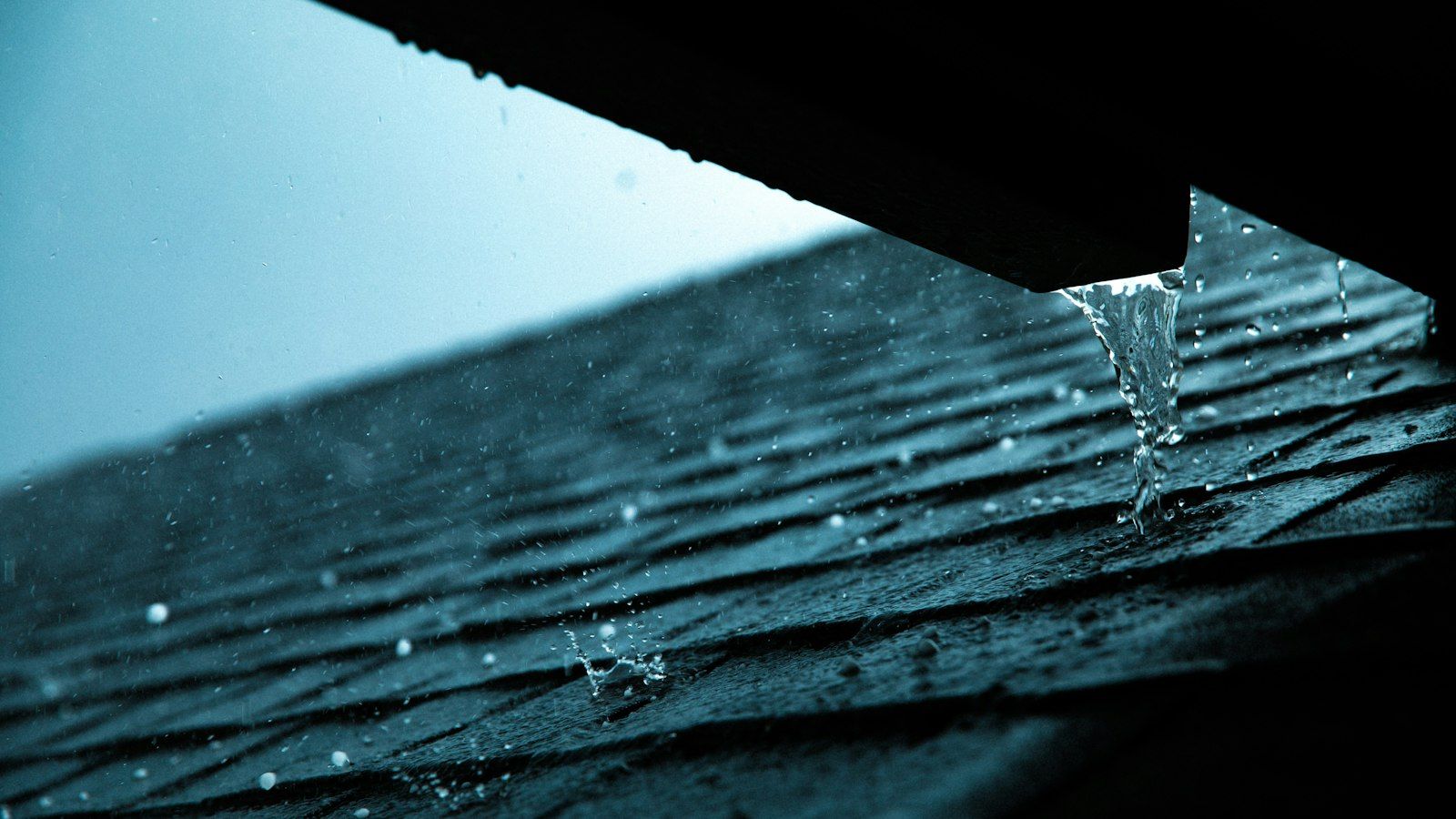 Rainwater running off the edge of a shingle roof